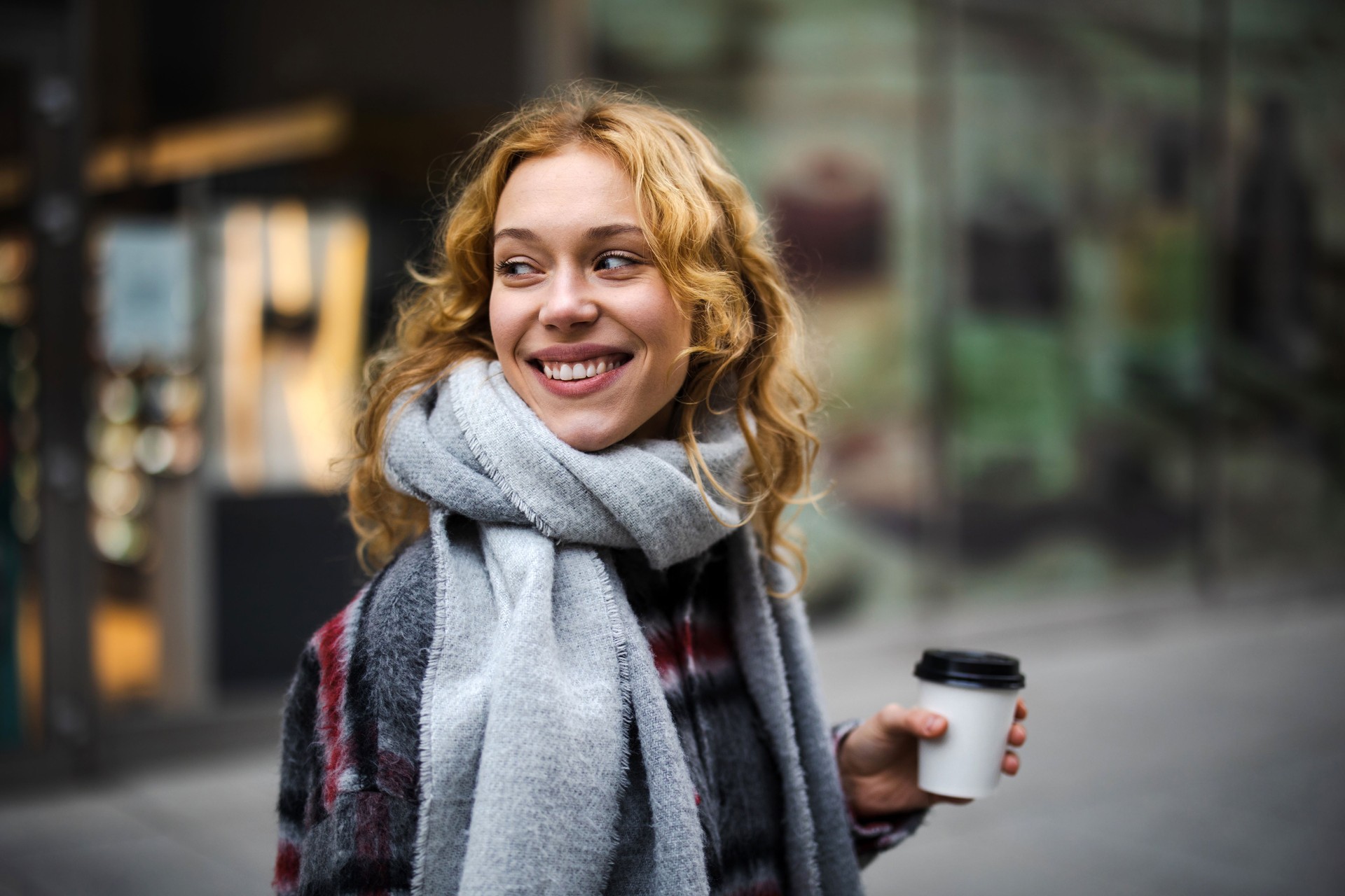 Young woman with coffee cup smiling outdoors